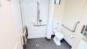 Un baño moderno con ducha, inodoro y barras de apoyo.
