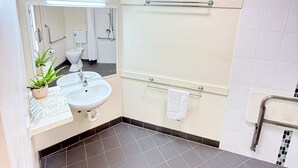 Une salle de bain moderne équipée d’un lavabo, d’un miroir, d’un porte-serviettes et d’un espace douche.