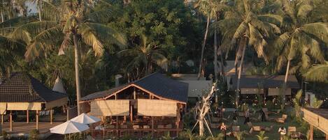 A resort with a pool, lounge chairs, umbrellas, and palm trees.