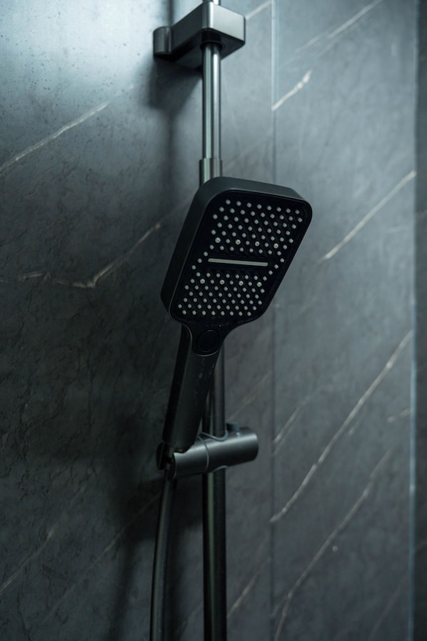 A showerhead with a square, perforated design mounted on a wall with a marble-like texture. - Vela Tianyar Boutique Resort By Dhananjaya Hospitality (Kubu)