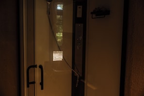 A narrow hallway with a door on the left, a small window, and a wall-mounted control panel. - Vela Tianyar Boutique Resort By Dhananjaya Hospitality (Kubu)