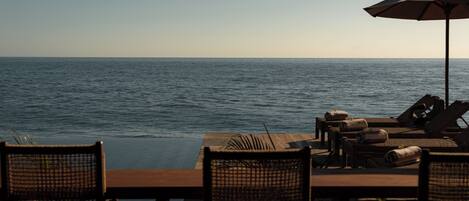 Una piscina al aire libre, sombrillas, sillones reclinables de piscina