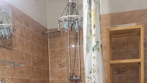 A bathroom with a shower, a sink, a toilet, and a shelf with toiletries. - STUDIO BARBOTAN-LES-THERMES (Cazaubon)