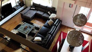 Una sala de estar moderna con un sofá modular, un televisor de pantalla plana y un comedor con mesa y sillas.