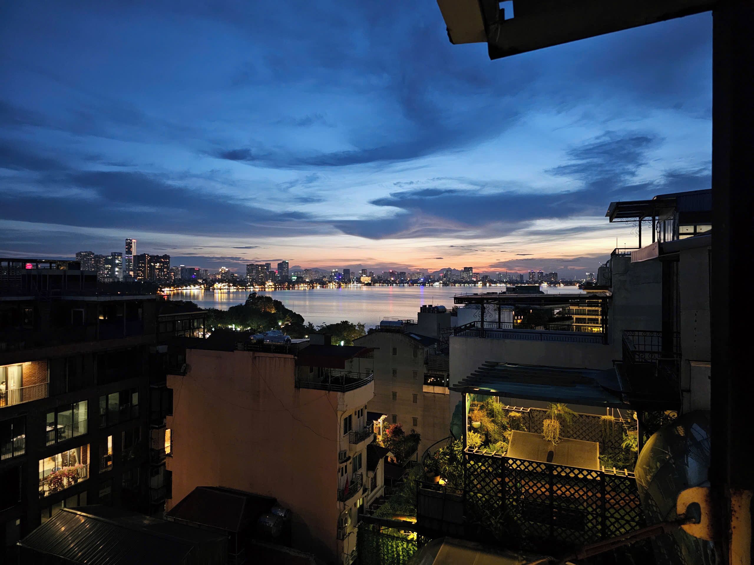 A cityscape at dusk with buildings and a waterfront.