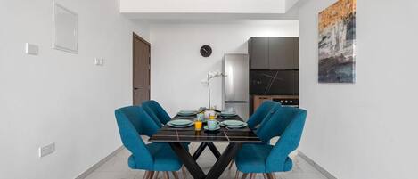 A modern dining area with a black table, blue chairs, and a clock on the wall.