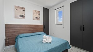 Une chambre à coucher comprenant un lit, une armoire et deux œuvres d’art murales.