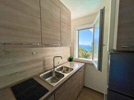 Una cocina moderna con armarios de madera, un lavamanos doble y un ventanal con vistas al mar.