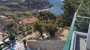 Una propiedad costera con una escalera de piedra que conduce a una terraza, con vistas a la costa rocosa y al mar.