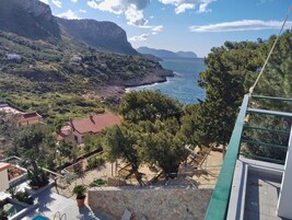 Una propiedad costera con una escalera de piedra que conduce a una terraza, con vistas a la costa rocosa y al mar.