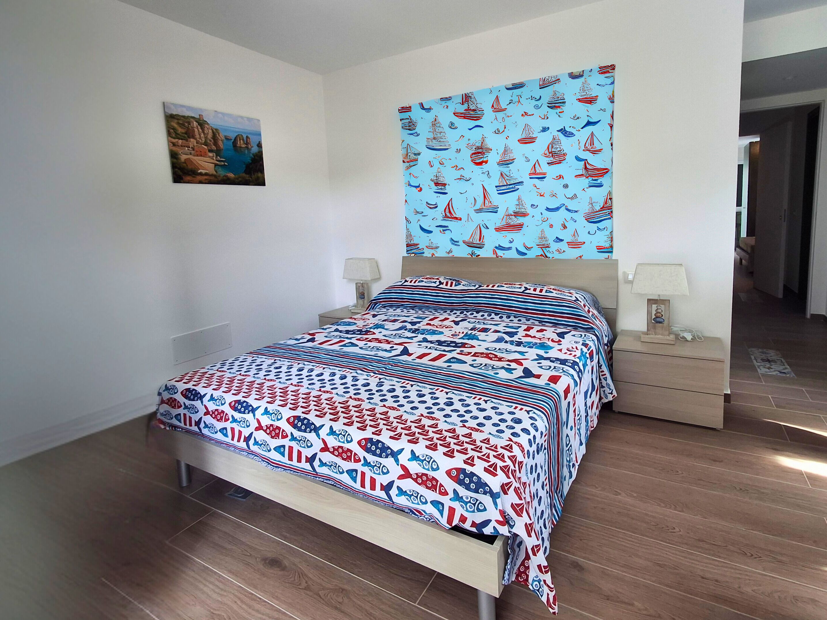 Un dormitorio con una cama, dos mesitas de noche, una lámpara de pared y un cuadro enmarcado.