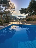 Una piscina con vistas despejadas al mar y montañas al fondo.