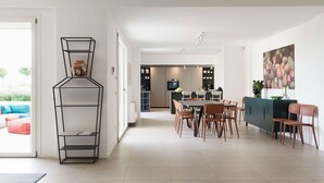 A modern kitchen with a dining area, featuring a central island, chairs, and a kitchen island with a built-in oven. - Villa Bel Prato with pool - My Rental Homes (Modica)
