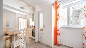 A modern kitchen with a dining area, a built-in oven, and a window with a view. - Studio in Vodice Near Male Vrulje Beach (Vodice)