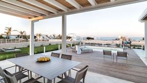 An outdoor patio with a pool, dining area, and beach view. - Villa Orietta, garden and pool - My Rental Homes (Noto)
