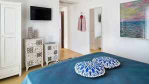 A bedroom with a bed, a dresser, a TV, and a painting. - Villa Orietta, garden and pool - My Rental Homes (Noto)