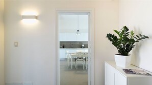 A modern kitchen with white cabinets, a dining area with white chairs, and a potted plant on a white cabinet. - Villa Emma with private pool - My Rental Homes (Marsala)