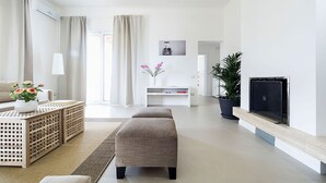 A modern living room with a sofa, ottoman, and a TV on a stand. - Villa Emma with private pool - My Rental Homes (Marsala)