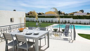 An outdoor dining area with a table set for four, overlooking a swimming pool. - Villa Emma with private pool - My Rental Homes (Marsala)