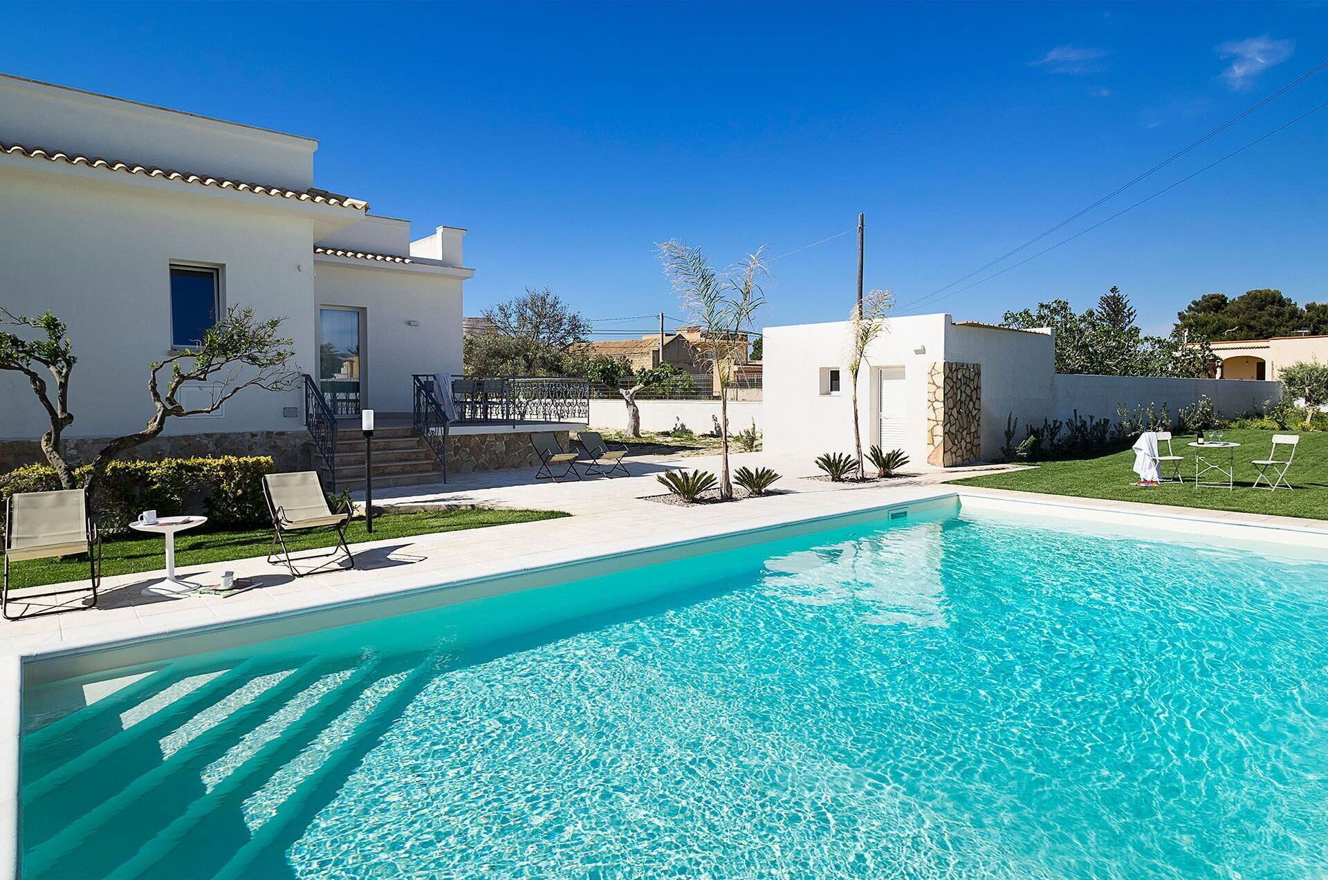 Una casa moderna con piscina, area relax esterna e giardino curato.
