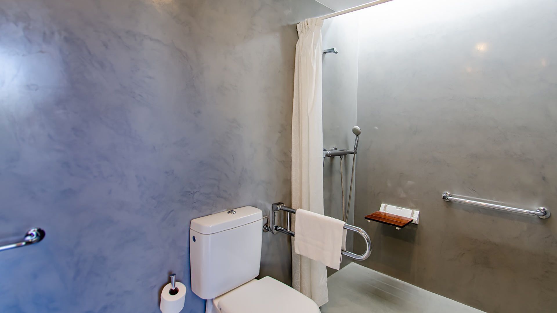 Een moderne badkamer met toilet, douche en handdoekrek.