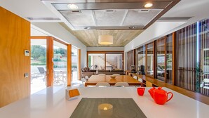 Un espace repas moderne avec une grande table, des chaises et une théière rouge.