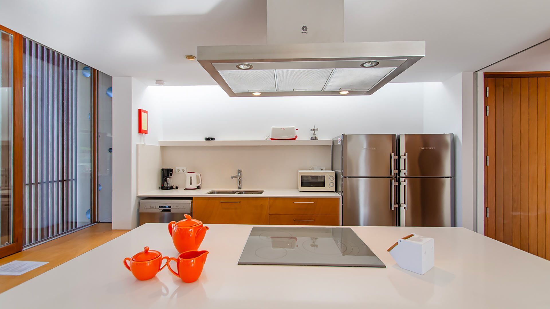 A modern kitchen with a central island, stainless steel appliances, and a sliding glass door.