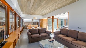 Un salon moderne avec deux canapés marron, une table basse en verre et un coin repas en bois.