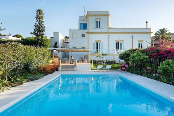 A modern two-story building with a swimming pool in the foreground. - The Flower Garden with pool - My Rental Homes (Marsala)
