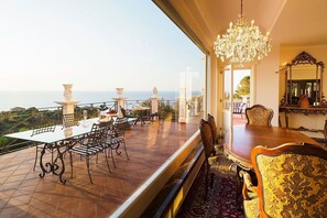 A luxurious dining area with a view of the sea, elegant furniture, and a grand chandelier. - Blue Star Villa with pool - My Rental Homes (Capo D'orlando)