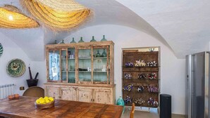 A dining area with a wooden table, a cabinet with glass doors, and a collection of figurines on shelves. - My Rental Homes - Finca Design 10-min drive from Mahon with swimming pool (Mahon)