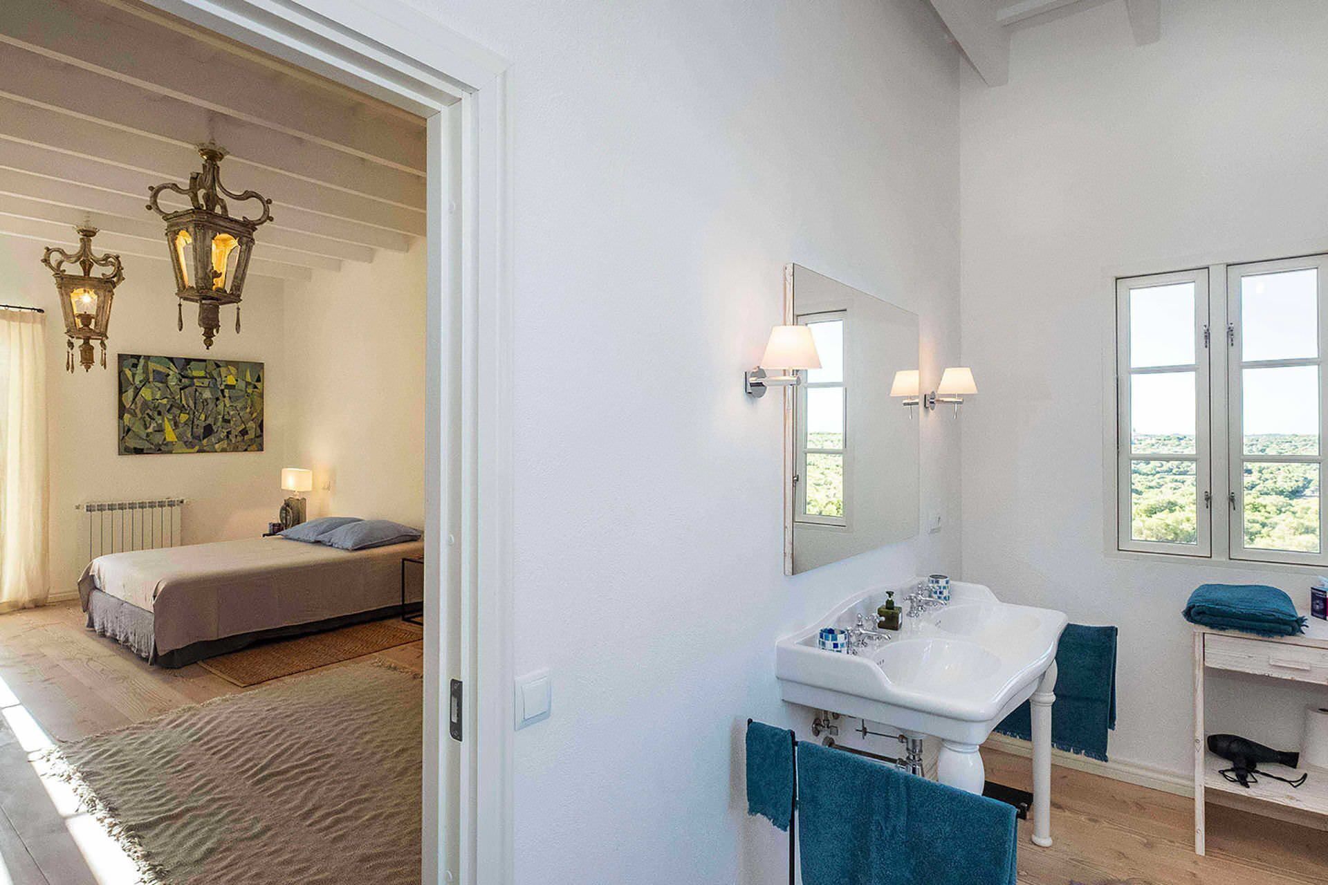 A bedroom with a bed, bedside lamps, a radiator, and a window.