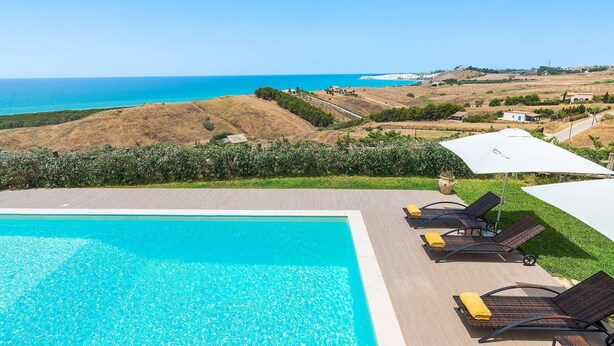 Ein Poolbereich mit Blick auf das Meer und die Hügel.