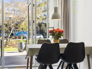 Un espace repas comprenant une table, des chaises, un vase avec des fleurs et un luminaire suspendu.