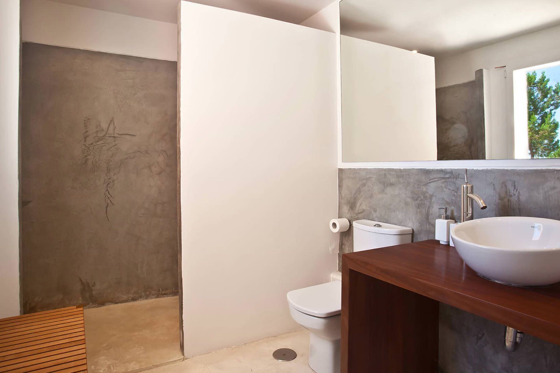 A modern bathroom with a large mirror, a wooden vanity, and a toilet.