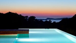 A infinity pool with a view of the sunset over water and hills. - My Rental Homes - Villa Twilight with private pool and sea view (San Jose)