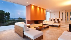 A modern living room with a large flat-screen TV, white sofas, a coffee table, and a dining area with chairs. - My Rental Homes - Villa Twilight with private pool and sea view (San Jose)