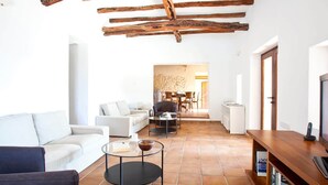 A spacious living area with a white sofa, a round coffee table, and a TV on a wooden stand.
