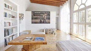 A spacious room with a wooden table, bookshelves, and a large window.