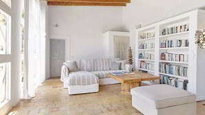 A cozy living room with a striped sofa, a wooden coffee table, and a bookshelf filled with books.