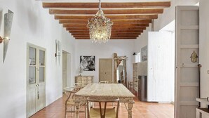 A rustic dining area with a wooden table and chairs, a chandelier, and a tiger painting on the wall.