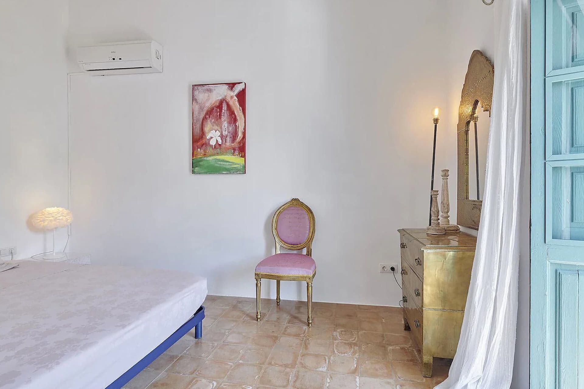A bedroom with a bed, a chair, a dresser, and a mirror.