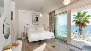 Ein modernes Hotelzimmer mit einem großen Bett, einem Nachttisch mit Lampe, einem Badezimmer mit Spiegel und einem Balkon mit Meerblick.