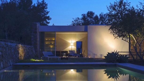 Un espace piscine extérieur moderne, doté de chaises longues et d’un mur en pierre.