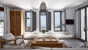 Ein modernes Wohnzimmer mit einer Couch, einem Couchtisch und Blick auf die Stadt durch große Fenster.