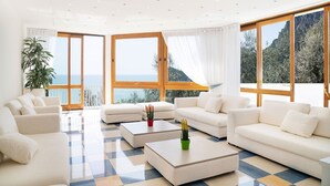 Ein geräumiges Wohnzimmer mit großen Fenstern, einem Schachbrettmuster-Boden und Meerblick.