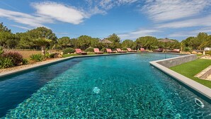 A clear blue pool with lounge chairs and a grassy area.