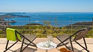 Una terraza con dos sillas plegables, una mesita y vistas al mar y a las colinas.