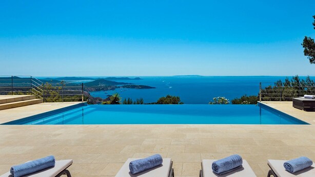 Una piscina infinita con vistas al mar y a islas distantes.