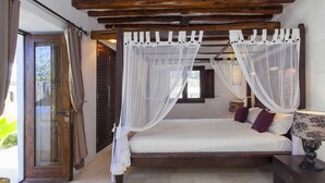 A bedroom with a wooden ceiling, a four-poster bed with white curtains, a bedside table with a lamp, and a view of the outdoors. - Villa in Santa Eulària Des Riu with 4 bedrooms sleeps 8 (Santa Eulària Des Riu)